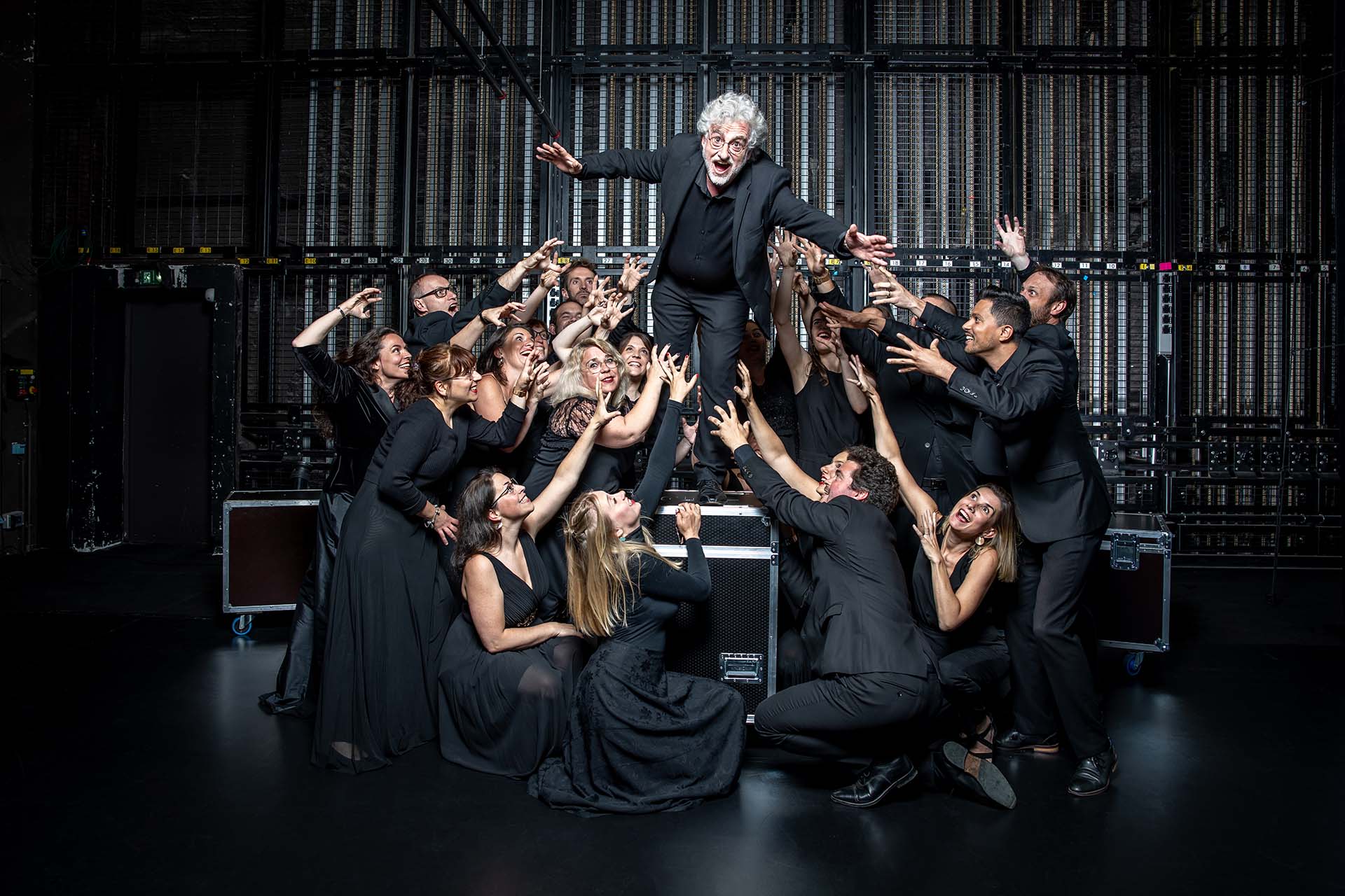 Photo de groupe du Chœur de chambre Mélisme(s) où Gildas Pungier, directeur, est au centre et mime de sauter, entourés des membres du chœur.